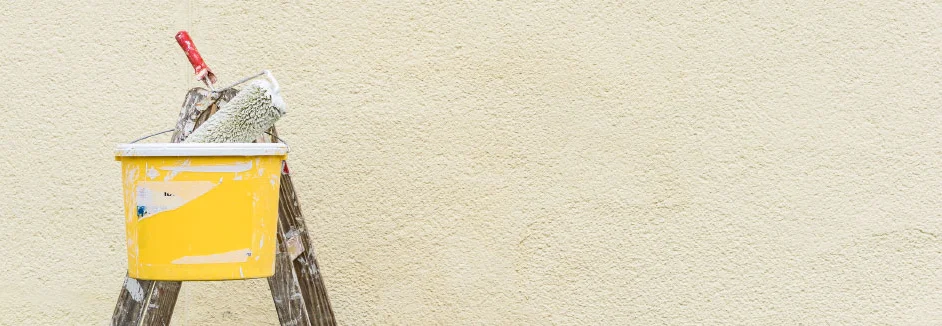 Farbeimer und Farbrolle auf Leiter